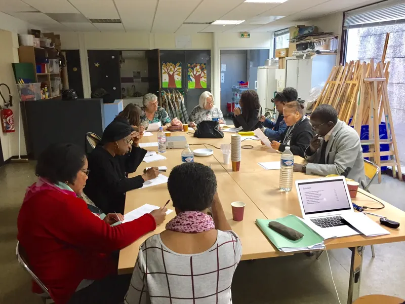Des participants échangent et prennent des notes autour d’une table lors d’un atelier participatif.